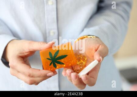 Le mani femminili tengono il vaso di pillole di marijuana Foto Stock