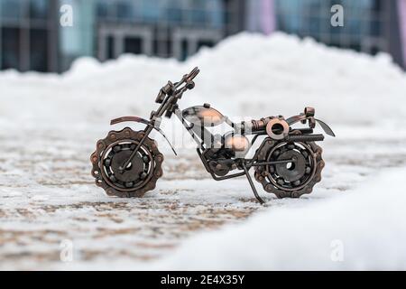 Il modello in bronzo metallico di un giocattolo sportivo per motociclette si erge una strada in cemento coperta di neve Foto Stock