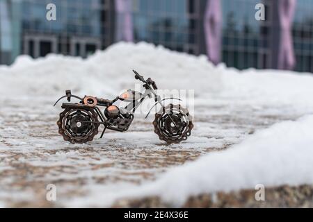 Il modello in bronzo metallico di un giocattolo sportivo per motociclette si erge una strada in cemento coperta di neve Foto Stock