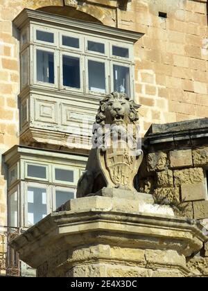 De Vilhena Lion statua simbolo della Valletta e i tradizionali balconi in legno in East Street, Malta Foto Stock