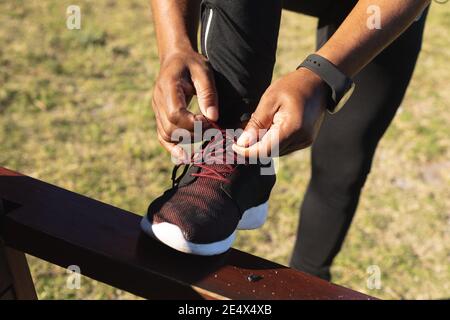 Sezione bassa dell'uomo africano americano anziano che esercita le scarpe di legatura. Sano ritiro stile di vita all'aperto di idoneità. Foto Stock