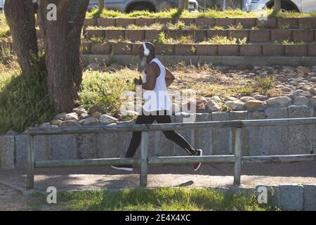 Indossa le cuffie wireless che corrono nel parco. Sano stile di vita all'aperto di riposo. Foto Stock