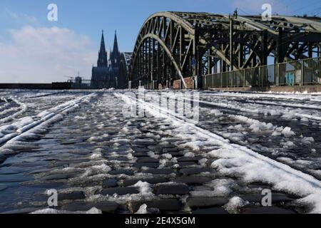 Sciogliendo la neve su un sentiero lastricato a Colonia, in Germania, con la famosa cattedrale sullo sfondo Foto Stock