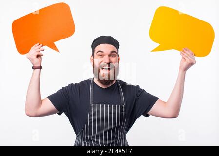 Foto di un cuoco ammanto in uniforme che tiene due bolle di parole. Foto Stock