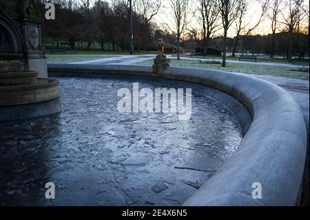 Glasgow, Scozia, Regno Unito. 25 Gennaio 2021. Nella foto: Si forma del ghiaccio sulla fontana nel Kelvingrove Park. Una mattina fredda e gelosa con temperature che si tuffano durante la notte a -2C, quando il sole sale, la temperatura sale solo a circa 1C in alcune zone con ghiaccio e gelo che copre il terreno. Un caldo bagliore mattutino ad ovest mentre il sole che sorge illumina la città, mostrando Kelvingrove Park e l'area del West End di Glasgow. Credit: Colin Fisher/Alamy Live News Foto Stock