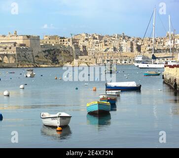 Kalkara, Malta - 28 novembre 2011: Lo skyline fortificato della Vecchia Valletta, in primo piano piccole barche e boe marine del porto di Kalkara - Malt Foto Stock