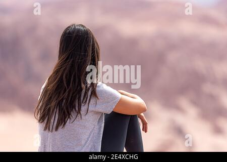 Indietro vista di una donna anonima che ammira le formazioni rocciose nel giorno nuvoloso nel deserto di Atacama, Cile Foto Stock