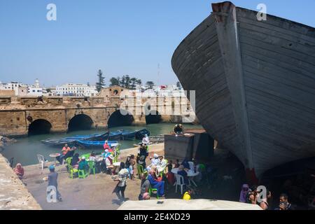 I turisti vengono serviti con pesce fresco sulla banchina del porto di Essaouira, Marocco Foto Stock