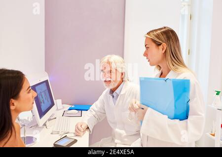 Medico e assistente medico in una consultazione con un paziente presso l'ufficio del medico Foto Stock