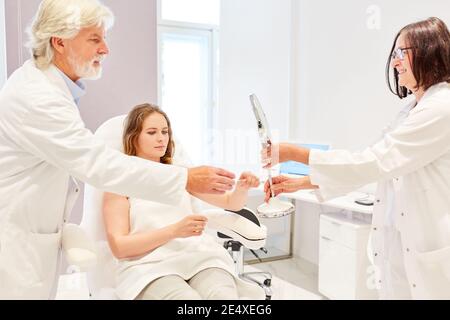 Team medico nella clinica di bellezza in una consultazione con il paziente prima del lifting Foto Stock