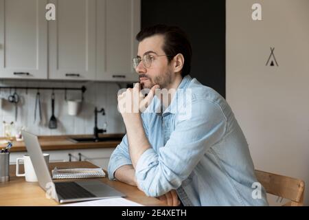 Giovane studente di sesso maschile pensante sul compito di apprendimento a distanza Foto Stock