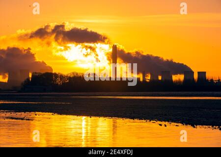 Alba in inverno su Drax nel North Yorkshire con il sole che sorge dietro un percorso di vapore acqueo dalle torri di raffreddamento di una centrale elettrica. Golden Refle Foto Stock