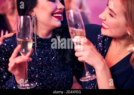 Due femmine gioiose che graffano i loro flauti di champagne Foto Stock