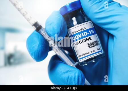 vaccino e siringa di covid-19 nel closeup della mano del medico Foto Stock