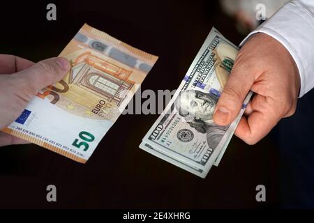 Le donne scambiano le banconote europee e il dollaro americano. Concetto di cambio di valuta. Foto Stock