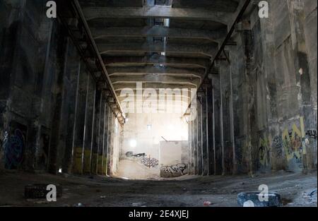 Sala oscura, vuota e grintosa abbandonata di una fabbrica distrutta Foto Stock