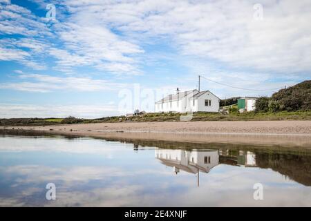 Bungalow sulla spiaggia sul fronte mare a riflessione in piscina di acqua di mare tranquillo sulla spiaggia di sabbia casa remota fuori dalla griglia con cielo blu paesaggio estivo Foto Stock