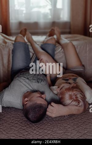 Felice giovane coppia che si guarda l'un l'altro e sorridente mentre si sdraiava sul pavimento. Il concetto di festeggiare San Valentino. Amore e relazioni Foto Stock