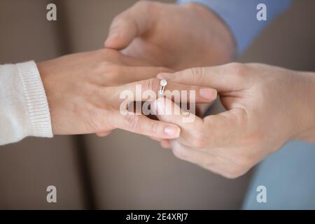 Primo piano uomo che mette l'anello di nozze sul dito della donna Foto Stock