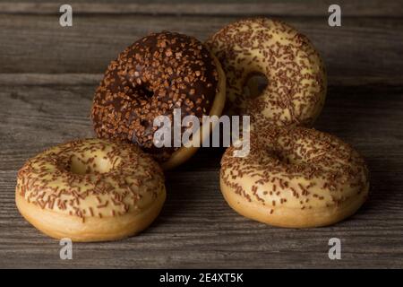 Un mazzo di ciambelle ad anello ricoperte di vaniglia e glassa al cioccolato, ricoperte di spruzzi. Foto Stock