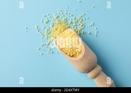 Cucchiaio con couscous crudo su blu in vista dall'alto, una luminosa ripresa aerea dei grani per ricette Foto Stock