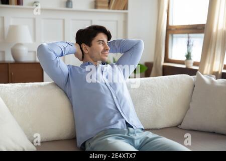 Primo piano soddisfatto giovane sognante che guarda da parte, rilassante Foto Stock