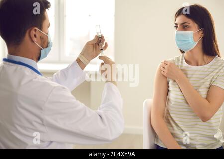 Medico che prepara la siringa con il vaccino durante la campagna di immunizzazione presso il clinica Foto Stock