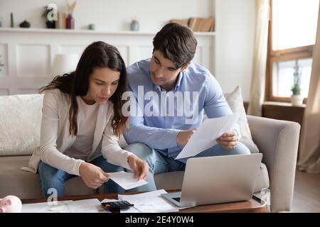 Primo piano giovane coppia che controlla i documenti finanziari, utilizzando il laptop Foto Stock