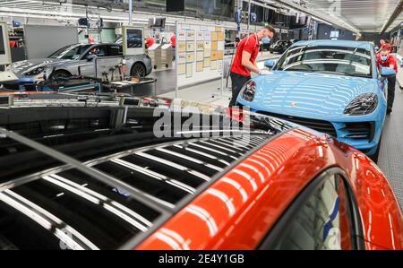 Lipsia, Germania. 07 maggio 2020. Indossando le protezioni per la bocca, i dipendenti Porsche effettuano il controllo di qualità finale su un Macan prima di uscire dalla linea di produzione. A Lipsia si applicano ora norme igieniche rigorose. Ad esempio, i dipendenti della produzione e della mensa dovrebbero indossare protezioni per bocca/naso. Si applica una distanza minima di 1.5 metri. Inoltre, la pulizia viene eseguita con maggiore frequenza rispetto a prima. Credit: Jan Woitas/dpa-Zentralbild/dpa/Alamy Live News Foto Stock