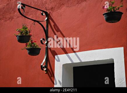 Tradizionale facciata coloniale con una parete in stucco veneziano e vasi di fiori di argilla appesi ad Atlixco, Puebla Messico. Foto Stock