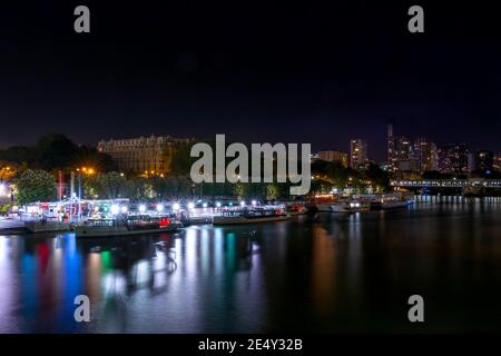 Francia. Notte estiva a Parigi. Le navi da diporto sono ormeggiate al lungofiume della Senna. Molte luci multicolore Foto Stock