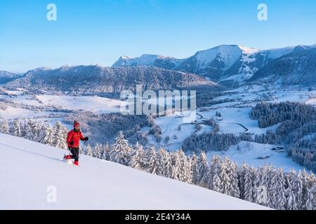 Bella donna anziana attiva racchette da neve nelle Alpi Allgaeu vicino Oberstaufen con vista sul Bregenzerwald, Vorarlberg, Austria Foto Stock