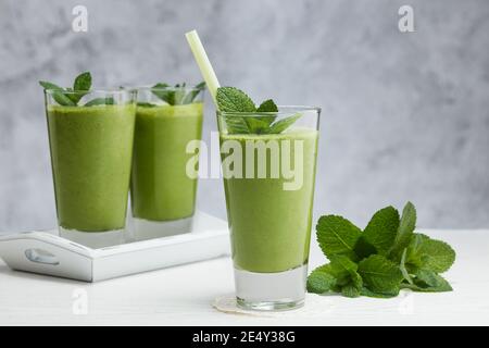 Bevanda sana. Frullati con banana, avocado, spinaci, lime su sfondo grigio. Foto Stock