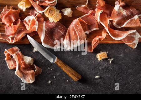 Fette di prosciutto su sfondo scuro. Vista dall'alto. Foto Stock