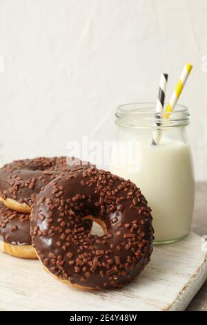 Vasetto di latte e gustose ciambelle sul tavolo grigio Foto Stock