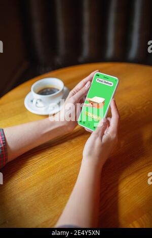 Tempo della pizza. Primo piano mani che tengono smartphone, cellulare con servizio di consegna cibo sullo schermo. Sicurezza durante la chiusura. Tecnologia moderna e assistenza sanitaria. Acquisti online, ordini di merci. Stile di vita. Foto Stock