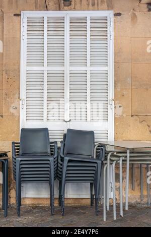Sedie in plastica grigia impilate accanto ai tavoli all'aperto. Il ristorante è chiuso dal Covid-19 Crisis Foto Stock