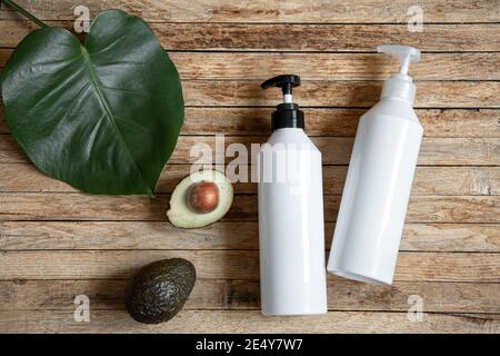 Still life con bottiglie bianche mock-up con dispenser e avocado. Cosmetici biologici e concetto di bellezza. Foto Stock