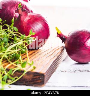 Cipolle rosse con timo su tavola di legno. Foto Stock