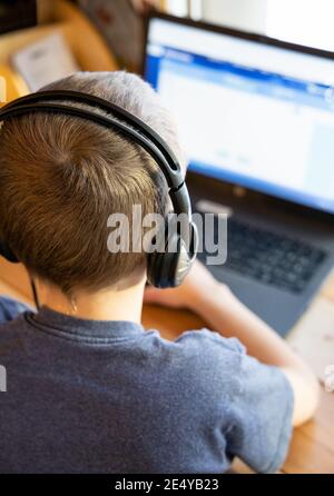 Un ragazzo lavora sul suo computer durante una scuola virtuale lezione Foto Stock