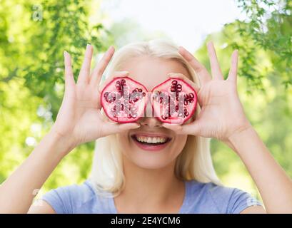 Donna felice che coprono gli occhi con melograno Foto Stock