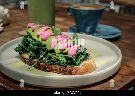 Toast all'avocado con spinaci, caffè e succo di frutta verde per la colazione Foto Stock