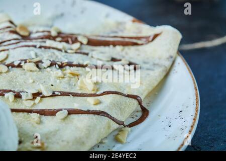 Pancake con gelato, spruzzare, cioccolato sulla piastra bianca su fondo scuro Foto Stock
