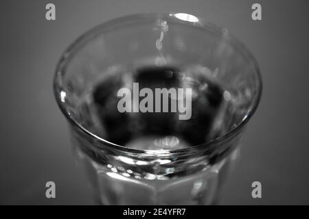 Parte superiore di un bicchiere pieno di acqua fresca su sfondo scuro. Mettere a fuoco il bordo di fronte Foto Stock