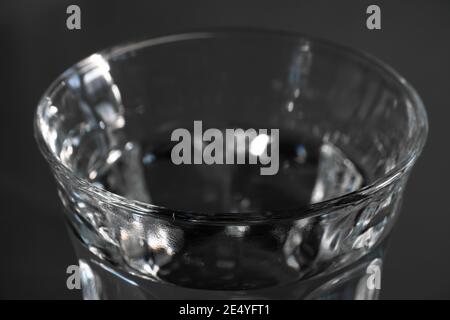 Parte superiore di un bicchiere pieno di acqua fresca su sfondo scuro. Mettere a fuoco il bordo di fronte Foto Stock