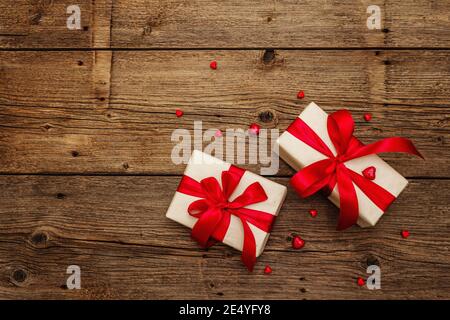 Sfondo del biglietto d'auguri di San Valentino con scatole regalo, nastri rossi e cuori assortiti. Tavolo in legno d'epoca. Concetto di matrimonio o compleanno, luogo per il testo Foto Stock