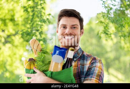 Sorridente giovane uomo con il cibo nel sacco Foto Stock