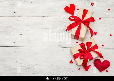 Sfondo del biglietto d'auguri di San Valentino con scatole regalo, nastri rossi e cuori assortiti. Vecchio sfondo di legno bianco. Concetto di matrimonio o compleanno, Foto Stock