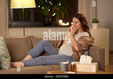 donna incinta malata che soffia il naso a casa Foto Stock