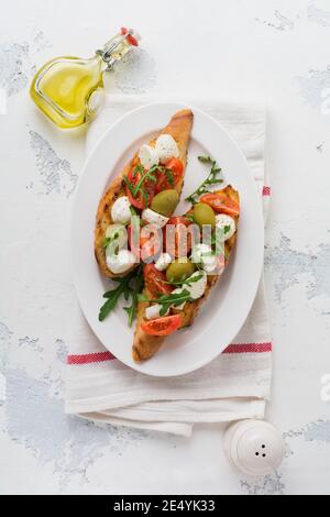 Bruschetta caprese con mozzarella, pomodori ciliegini, olive e rucola. Vista dall'alto con spazio per il testo Foto Stock